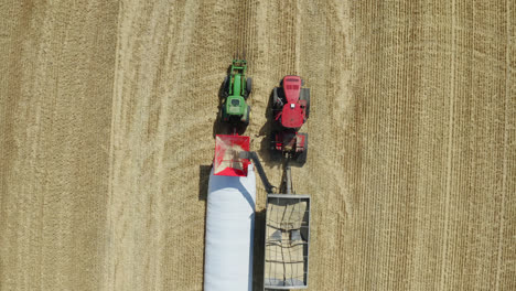 Bird's-eye-zoom-in-on-farming-equipment-harvesting-grain,-Saskatchewan,-Canada