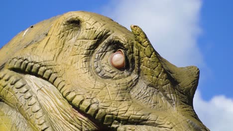 Riesiger-Dinosaurier-Mit-Geöffnetem-Mund-Gruselig-Aussehende-Braune-Grüne-Haut-Langer-Hals-Und-Zähne-Zoomen-In-Sein-Weißes-Rotes-Auge-Hell-Sonnig-Im-Freien