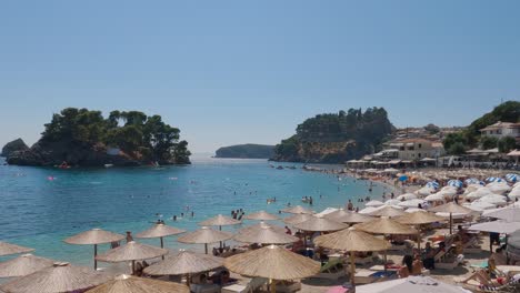 Panning-shot-of-tourists-relaxing-and-swimming-at-the-stunning-town-of-Parga,-Greece