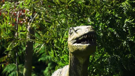Pequeño-Dinosaurio-Antiguo-Escondido-En-El-Pico-Del-Arbusto-En-Busca-De-Su-Presa-Hambrienta-Abriendo-La-Boca-Ojos-De-Miedo-Soleado-Cámara-Lenta