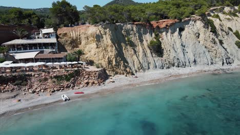 Aerial-Dolly-Rückansicht-Von-Der-Klippe-Am-Meer-über-Dem-Strand-Sol-Den-Serra-Auf-Ibiza
