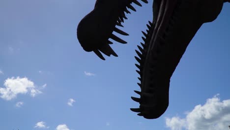 Nahaufnahme-Silhouette-Kopf-Des-Dinosauriers-Und-Große-Zähne-Beängstigend-Erschreckende-Szene-Altes-Historisches-Tier-Heller-Himmel-Mit-Wolken-Zeitlupe