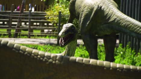 Aufschlussreiches-Gruseliges-Dinosauriermodell-Mit-Blutigen-Zähnen,-Einschüchterndes-Gesicht-Im-Dino-Park,-Das-Seine-Beute-In-Zeitlupe-Betrachtet