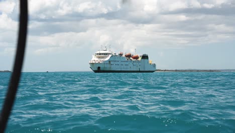 Rusty-cargo-ship-anchored-near-the-coastline-of-Zanzibar-Island-Tanzania-seen-from-a-small-boat,-Wide-angle-handheld-shot