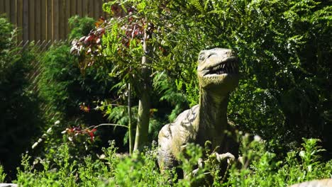 Reptil-Dinosaurio-Aterrador-Escondido-En-Los-Arbustos-Ansiedad-Por-El-Clima-Ventoso-Abriendo-La-Boca-Con-Dientes-Grandes-Paisaje-Verde-Vívido