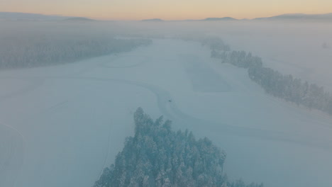 Norbotten-driver-drifting-corners-of-Lapland-ice-lake-aerial-view-through-blizzard-snow
