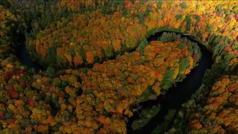 Drone-shot-of-fast-moving-shadows-over-snaking-river-and-forest-in-full-autumn-color