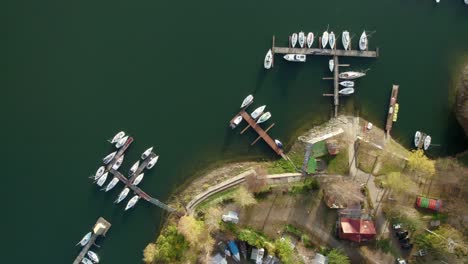 Aerial-top-down-view-of-many-recreational-boats-docked-at-a-lake-pier-at-sunset