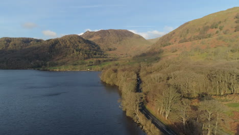 Aerial-Drone-Shot-over-Ullswater-Lake-of-A592-Road-with-2-Cars-Driving-Past-on-Sunny-and-Cloudy-Morning-Lake-District-Cumbria-United-Kingdom