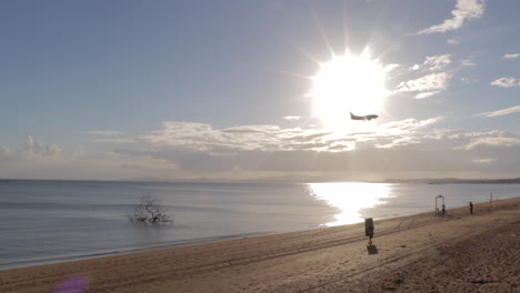 Flugzeug-Nähert-Sich-Dem-Flughafen,-Während-Es-über-Strand-Und-Ruhiges-Meerwasser-Mit-Strahlender-Sonne-Fliegt