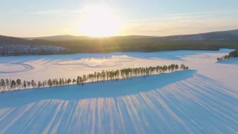 Long-sunrise-shadows-across-Lapland-Polar-circle-snow-covered-racetrack-surface-aerial-view