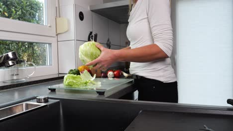 Frau-In-Der-Küche,-Die-Blätter-Von-Eisbergsalat-Für-Salat-Trennt