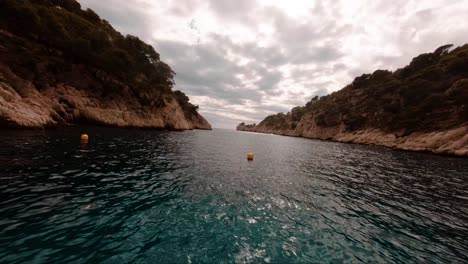 FPV-aerial-view-flying-through-the-river-valley-that-leads-to-the-mediterranean-ocean-in-Cassis,-France