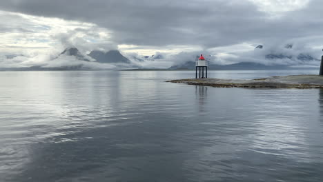 Clouds-surrounding-the-mountains-of-the-Helgeland-coast-during-rain-with-a-lighthouse-and-a-small-island