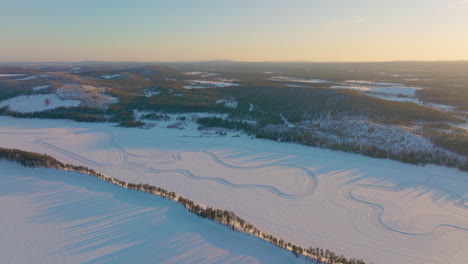 Lange-Sonnenaufgangsschatten-über-Dem-Polarkreis-Lapplands-Schneebedeckte-Treibende-Rennstrecke,-Die-Die-Luftaufnahme-Umkreist