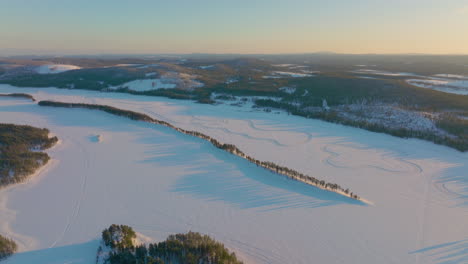 Sunrise-long-shadows-across-Lapland-Polar-circle-snowy-drifting-racetrack-aerial-view
