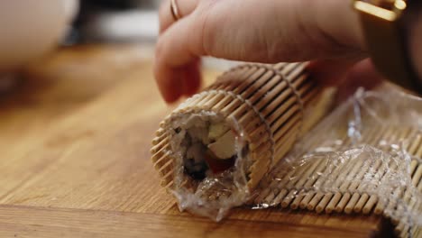 Rolling-sushi-on-a-makisu-in-closeup,-homemade-seafood