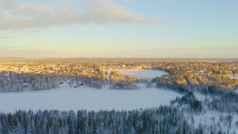 Warm-dressed-person-standing-overlooking-sunlit-Arvidsjaur-frozen-ice-lake-landscape-at-sunrise