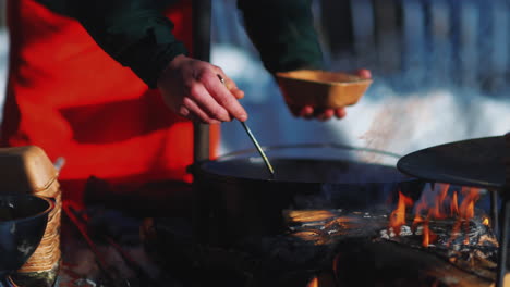 Man-serving-steaming-bowl-of-moose-soup-outside-for-seasonal-Swedish-meal
