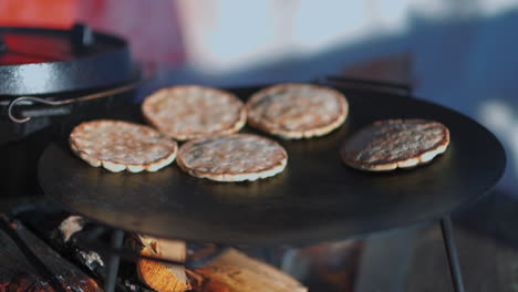 Traditional-Hällakakor-flatbread-baking-on-flat-log-fire-stove-plate,-Sweden