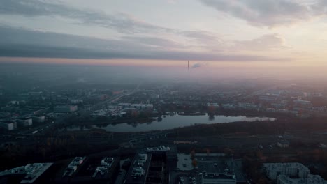 Aerial-view-of-foggy-sunrise-over-industrial-district-and-industrial-chimneys