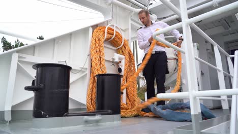 Captain-preparing-mooring-rope-onboard-for-use-onboard-passenger-ship---Low-angle-static-clip-of-person-uncoiling-rope-from-storage-position