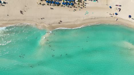 Aerial-view-above-waves,-turqouise-sea-and-a-beach,-in-sunny-Cancun,-Mexico---cenital,-drone-shot