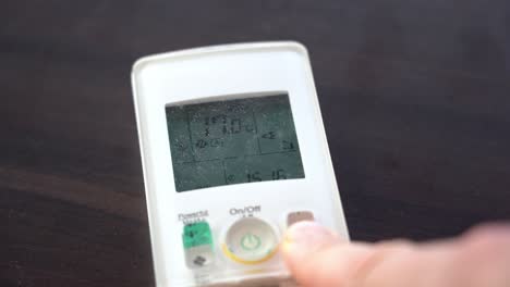 Reducing-room-temperature-on-heat-pump-remote-while-laying-on-table---Blurred-finger-in-foreground-with-temperature-on-remote-in-focus