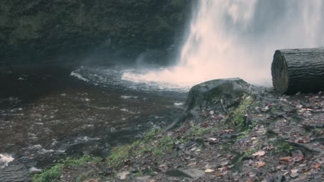 Enorme-Cascada-Estrellándose-Con-Tocón-De-árbol-Cortado-Y-Troncos-Y-Río-En-Gales,-Reino-Unido