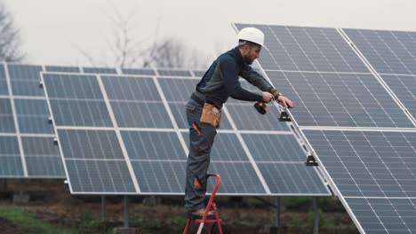 A-man-in-a-work-uniform-installs-a-solar-panel-at-a-solar-power-plant