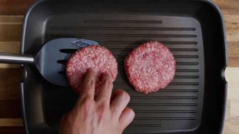 Top-down-shot-of-a-man-cooking-and-flipping-hamburger-meat-on-a-frying-pan-with-a-spatula,-faceless