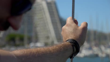 Slowmotion-rotating-shot-of-a-sailor-leaning-against-a-metal-cable-on-a-boat