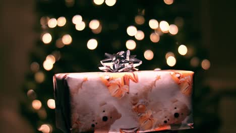 Regalo-De-Navidad-Giratorio,-Luces-Parpadeantes-En-El-árbol-De-Navidad-En-El-Fondo
