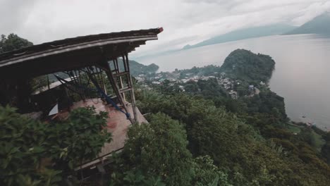 Terrace-on-hillside-with-view-to-Atitlan-lake-and-volcano,-aerial-FPV-view