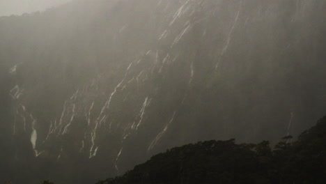 Numerous-waterfalls-flow-down-a-cliff-face-shrouded-by-clouds-during-heave-rain