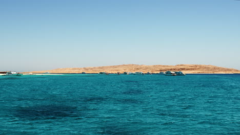 Fliegen-über-Dem-Blauen-Wasser-Des-Roten-Meeres-Mit-Blick-Auf-Die-Küste-Von-Hurghada-Gegen-Den-Blauen-Himmel-In-Der-Ferne