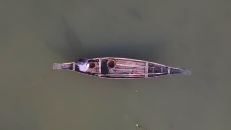 Top-down-aerial-view-of-small-traditional-Asian-fishing-wooden-boat,-zoom-out