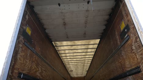 Tilt-down-view-inside-an-empty-white-semi-truck-cargo-trailer,-handheld