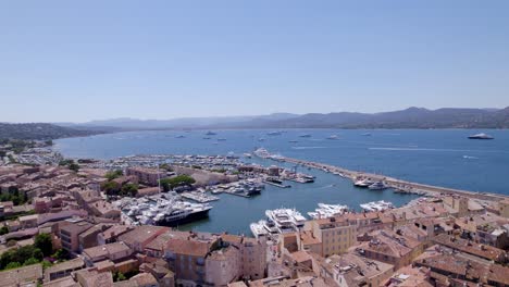 Aerial-forward-flight-over-city-of-Saint-Tropez-with-harbor-and-luxury-yachts-in-summer