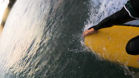 Close-up-shot-of-a-yellow-surf-board-with-a-man's-legs-while-surfing-in-Mui-Ne,-Vietnam-at-daytime