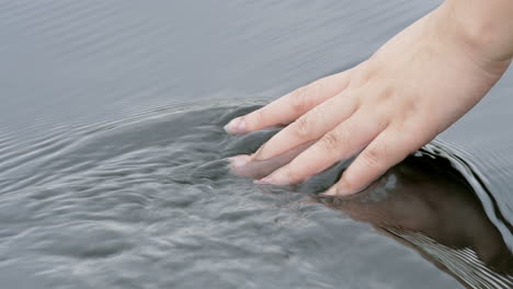 Hand-touching-water-in-the-forest-river-or-lake