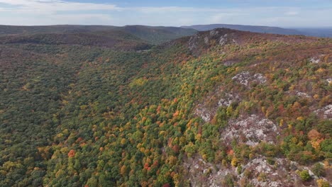 An-aerial-view-high-over-Storm-King-Mountain-in-upstate-NY-during-the-fall,-on-a-beautiful-day-with-white-clouds
