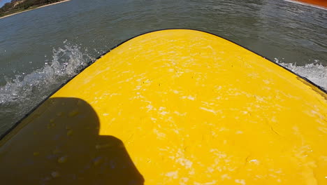 Close-up-shot-of-of-a-yellow-surf-board-along-the-sea-shore-in-Mui-Ne,-Vietnam-on-a-bright-sunny-day