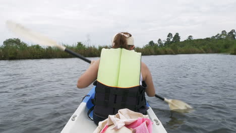 Happy-young-Asian-woman-kayaking-in-a-mangrove-forest-on-summer-travel-vacation-paddle-on-a-canoe-boat-in-a-forest-lake