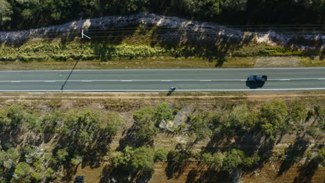 Aerial-Drone-Top-Down-View-Of-Athlete-Cyclist-Being-Overtaken-By-Car-On-Countryside-Highway,-4K