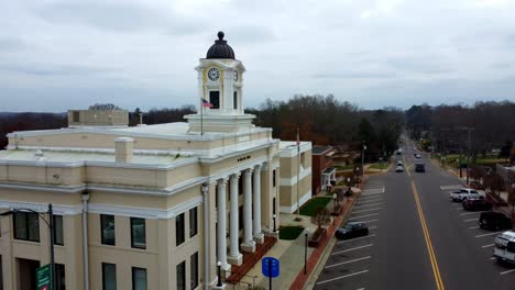 Mocksville-North-Carolina-Courthouse-reverse-Aerial-with-American-Flag-in-shot,-small-town