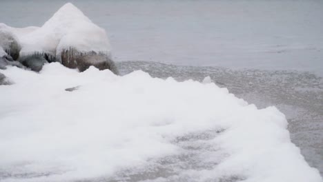 Static-shot-of-ice-waves-hitting-ice-shelf-and-ice-covered-rocks