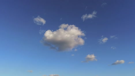 Schwenken-Nach-Unten-Vom-Blauen-Himmel-Mit-Weißen,-Flauschigen-Kumuluswolken