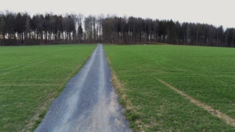 Flying-over-gravel-road-between-agricultural-field-in-Germany