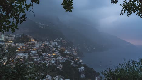 Time-lapse-monsoon-rain-approaches-the-coast-of-Positano,-Italy,-skillfully-framed-by-trees